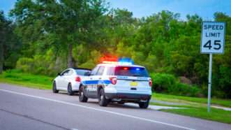 A police car with lights flashing pulls a car over. | Mike2focus/Dreamstime