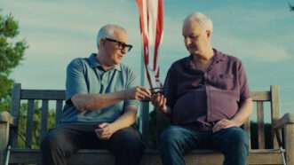 Two men sitting on a bench with one of them wearing Meta glasses | Photo: Meta
