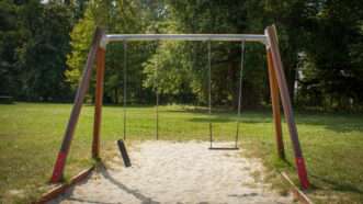 A swing set with two swings, one of which has a broken chain. | Dennis Van De Hoef/Dreamstime