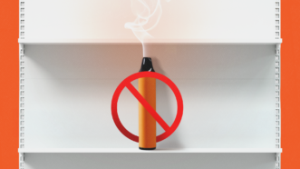 A vape with a ban symbol across it sits on a white shelf against an orange background | Botond Visnyei/Dreamstime/Fox Dsign/user13015019/Magnific/Mariam Zakaidze