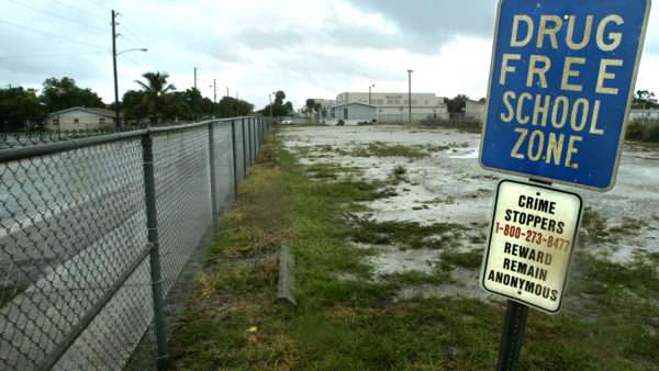 A 'drug free school zone' sign stands on a post next to a fence | David Spencer/ZUMA Press/Newscom