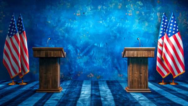 An AI-generated image of two wooden lecterns on a debate stage, flanked by American flags. The background is blue, and the stage floor resembles the stripes of the American flag. | Eduard Goricev | Dreamstime.com