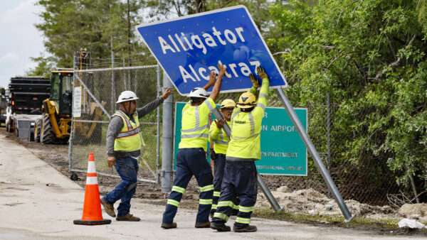 Workers raise a road sign that reads 'Alligator Alcatraz' | Al Diaz/TNS/Newscom