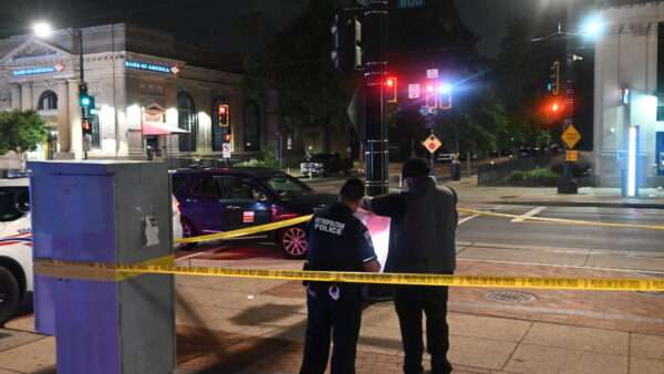 Two investigators with the Washington, D.C., Metropolitan Police Department stand behind yellow tape at the scene of a stabbing. | Kyle Mazza, Kyle Mazza/ZUMAPRESS/Newscom