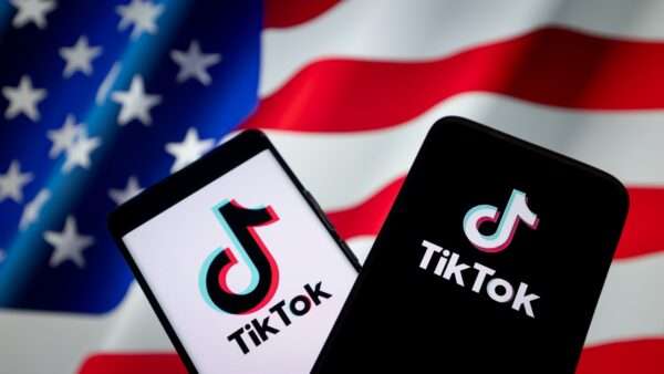 Two smartphones with the TikTok logo on screen, in front of an American flag background | LI HONGBO/FEATURECHINA/Newscom