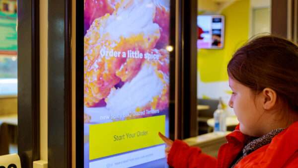 A young girl orders food from a McDonald's self-service kiosk. | Photovs | Dreamstime.com