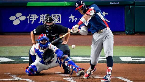 Aaron Judge, in a USA jersey, swings at a baseball in front of a catcher from the Dominican Republic and an umpire. | Photo: Michael Laughlin/UPI/Newscom