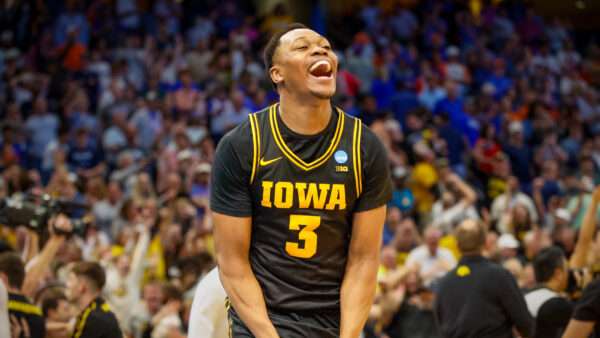Iowa Hawkeyes forward Cam Manyawu celebrates on a basketball court, with a crowd of fans behind him. | Photo: Jefferee Woo/ZUMA Press/Newscom