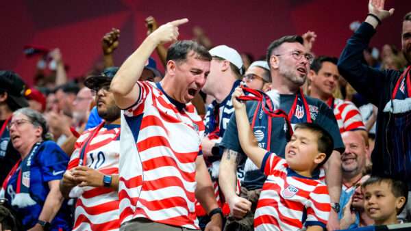 Fans of all ages and various races celebrate in the stands, wearing U.S. Soccer jerseys with wavy red stripes. | Photo: Billy Schuerman/Cal Sport Media/Newscom