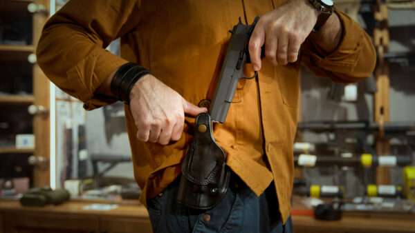 A man in a gun store pulls a semiautomatic handgun from a holster. | Ingram Publishing/Newscom