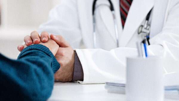 A doctor holding the hand of a patient | Igor Mojzes/Dreamstime.