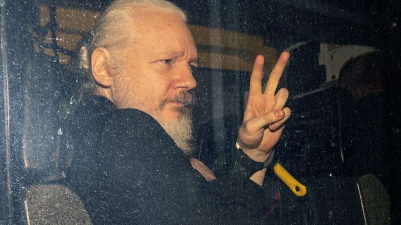 Julian Assange making a peace symbol in a car | News Licensing/Mega/Newscom