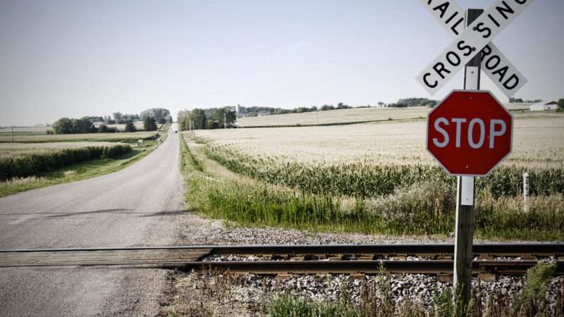 Rural railroad crossing in front of dirt roads and fields