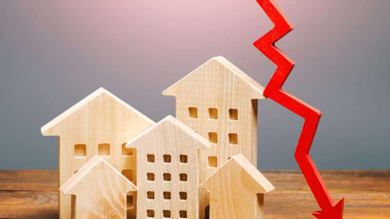 wooden houses sitting on a wooden shelf with a red arrow pointing down next to them