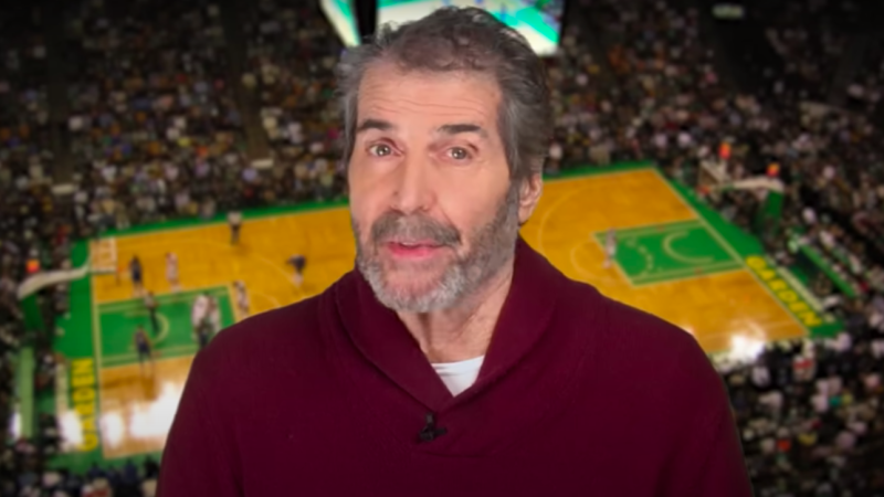 John Stossel is seen in front of a basketball court
