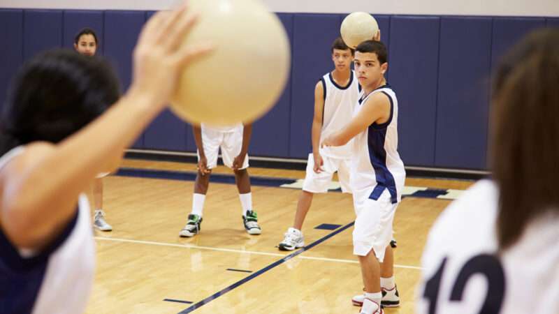 Students in P.E. clothes play dodgeball.