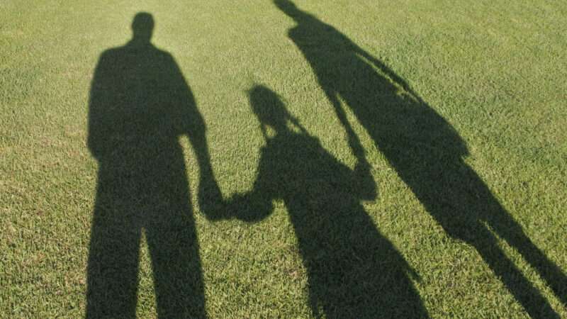 Family in shadow on green grass.