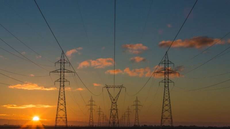 Electric transmission lines in front of a sunset | Photo by Matthew Henry on Unsplash