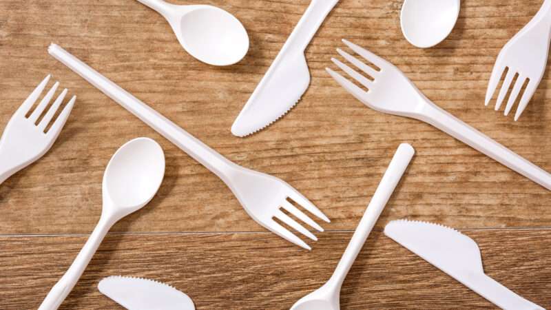 Plastic cutlery on a wooden table.