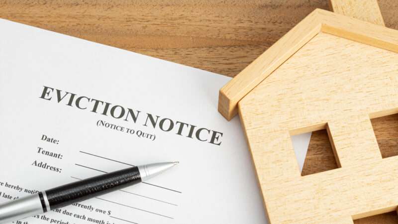 An eviction notice and a toy wooden house.