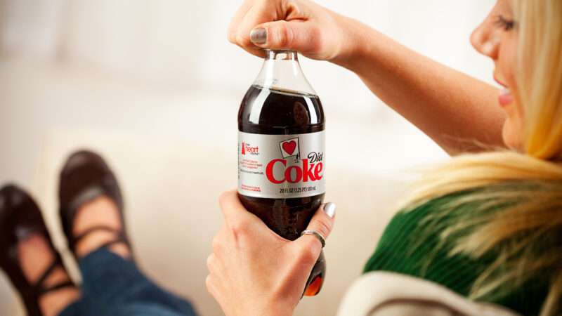 A woman with blonde hair opening a plastic bottle of Diet Coke. | Photo 46304455 © Seanlockephotography | Dreamstime.com