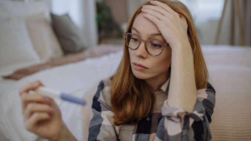 stressed-looking young woman looking at pregnancy test