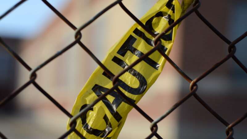 A piece of yellow CAUTION tape in a chain link fence. | Danhussey5 | Dreamstime.com