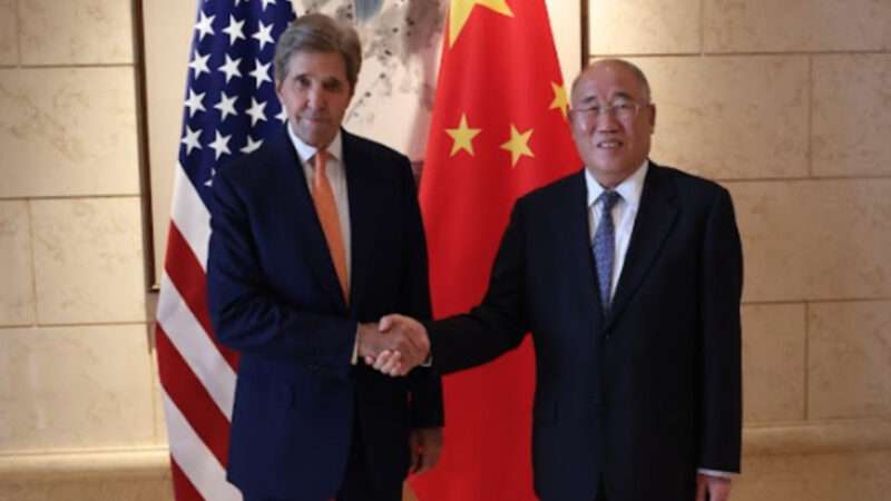 John Kerry shakes hands with PRC Special Envoy for Climate Change Xie Zhenhua in front of flags for the United States and China | State Department