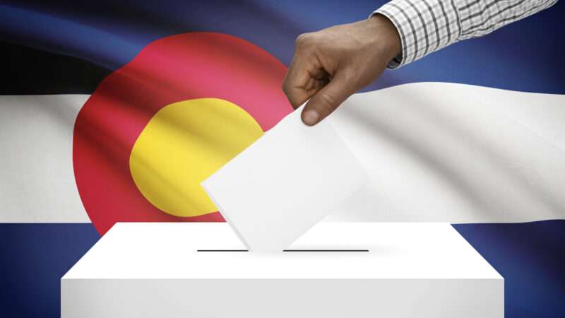 Voter casting a ballot in front of the Colorado state flag | DPST/Newscom