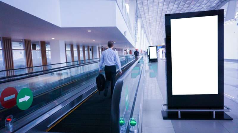 An airport moving sidewalk with a blank advertisement space next to it. | Anusorn Abthaisong | Dreamstime.com