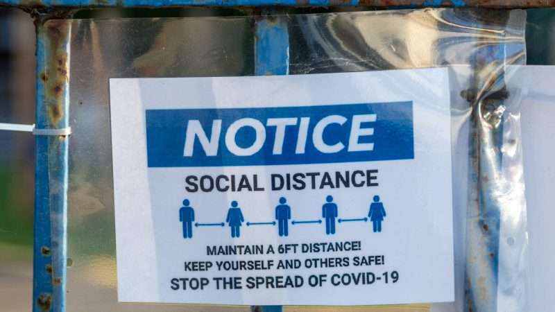 A sign on a fence advising people to social distance and stay six feet apart in order to stop the spread of COVID-19 | Gary Hider | Dreamstime.com