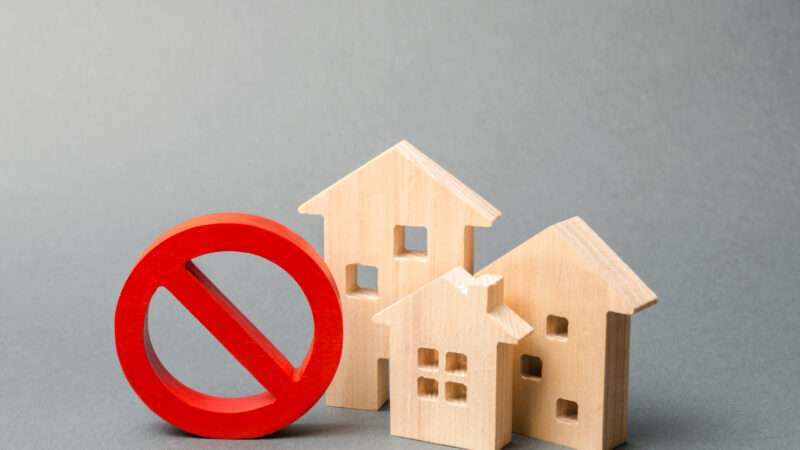 Wooden block homes with a ban sign | Andrii Yalanskyi/Dreamstime.com