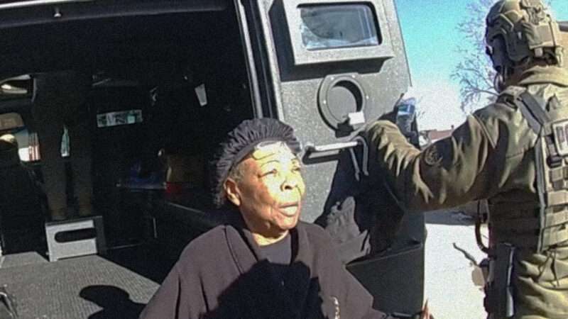 Ruby Johnson sits on the bumper of a vehicle with its back doors open while a man wearing camo holds one door open | CNN
