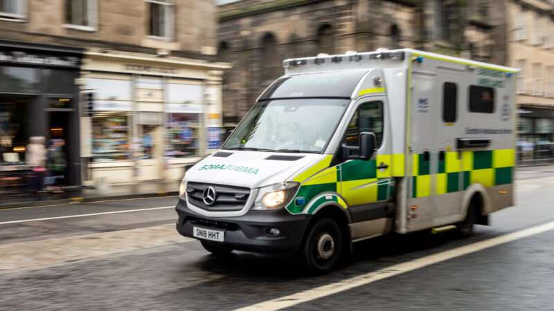 Ambulance drives down an Edinburgh street, blurred as if it's moving quickly. | Mino Surkala | Dreamstime.com