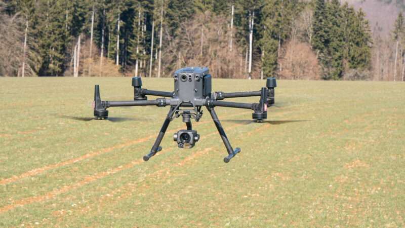 A DJI Matrice M300 drone in flight over a grassy field. | Marian Gh Moise | Dreamstime.com