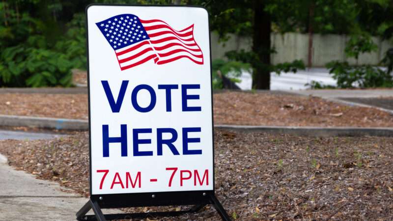 A sign for a polling place that reads VOTE HERE 7AM-7PM | Carol Hudson | Dreamstime.com