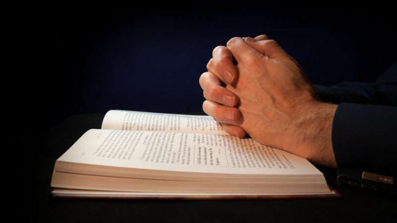 Hands clasped in prayer over a Bible. | Duncanandison | Dreamstime.com