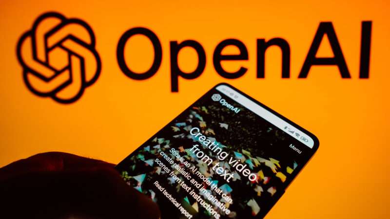Open AI app on smartphone, in front of a larger company logo | Rafael Henrique/ZUMAPRESS/Newscom
