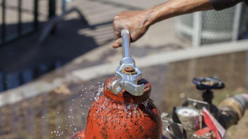 A person shuts off a fire hydrant by tightening it closed with a wrench. | Mary Sullivan | Dreamstime.com