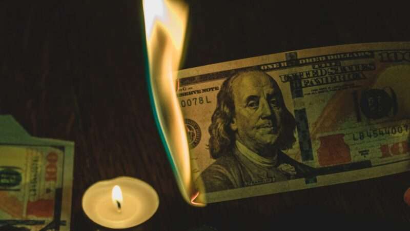 a hundred dollar bill, lit on fire | Photo by Gabriel Meinert on Unsplash