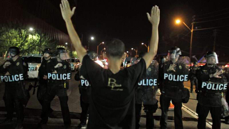 protester standing in front of riot cops with hands raised | Ricardo Arduengo/ZUMA Press/Newscom