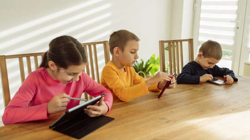 Three young children using mobile devices | Ok Shu/Westend61 GmbH/Newscom