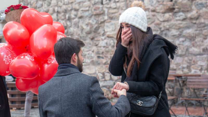 A man, down on one knee, proposes to a stunned woman. | Tunahan Karadongel | Dreamstime.com