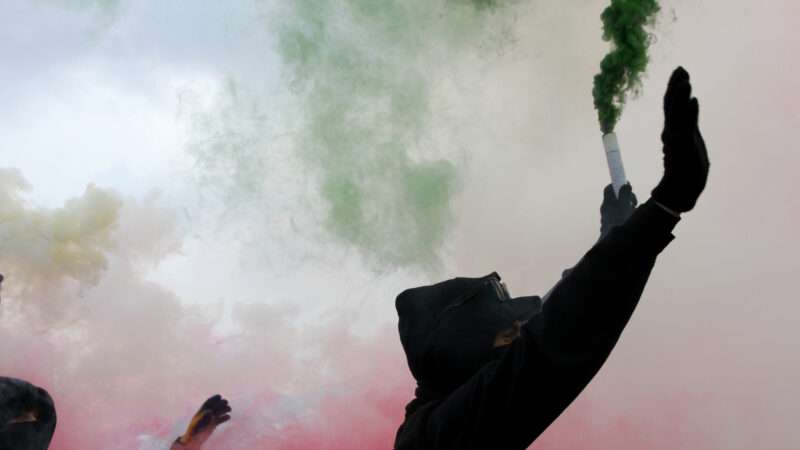 Protesters in silhouette amid red and green smoke | Fedecandoniphoto | Dreamstime.com