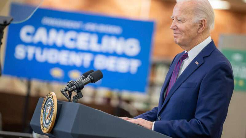 Joe Biden in front of a sign that says 