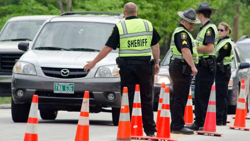 Police officers flag down cars at a DUI checkpoint. | Dmcdesign | Dreamstime.com