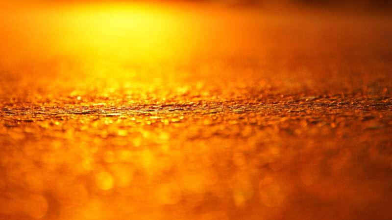 The orange glare of the sun against hot asphalt, in close-up. | Kirill Karpov | Dreamstime.com