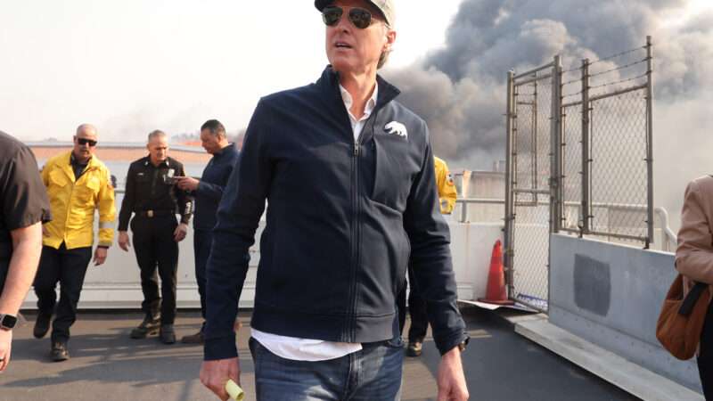 California Governor Gavin Newsom tours Pacific Palisades during the second day of the Palisades fire. Smoke and workers can be seen behind him. | Jonathan Alcorn/ZUMAPRESS/Newscom