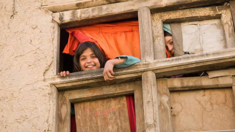 A happy child pokes their head through a high window in Kabul, Afghanistan. | Tim Gurney | Dreamstime.com