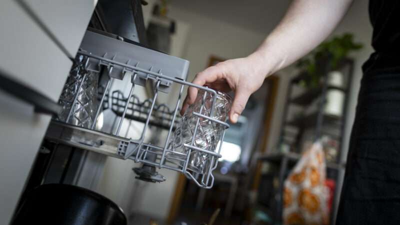 A hand pulls out the top rack of a dishwasher | picture alliance / Kira Hofmann/photothek.de/Newscom